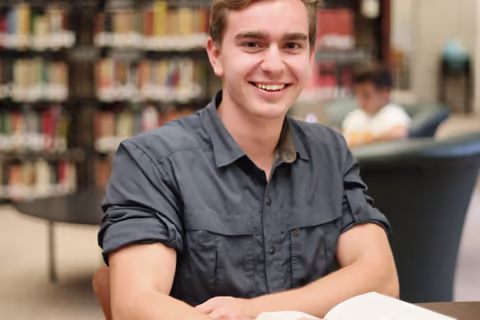 Student sitting at desk in front of bookcases