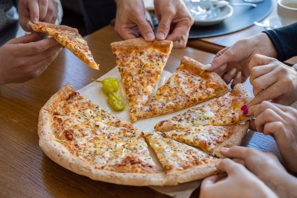 Hands grabbing slices of cheese pizza