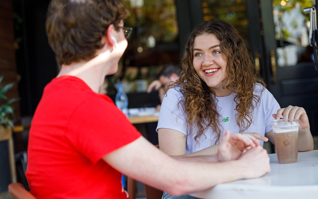 two students talking and drinking coffee