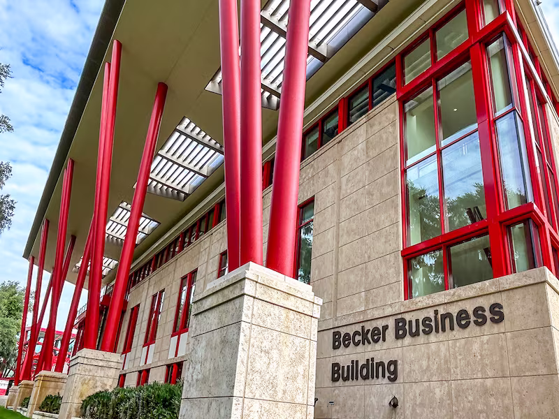 Low angle exterior photo of the Becker Business Building against a bright blue sky.