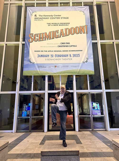 steven emery posing in front of "Schmigadoon" banner